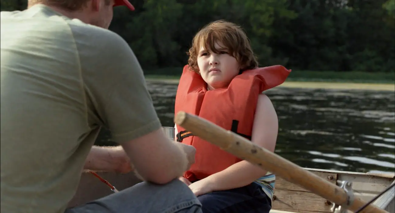 Cooper J. Friedman as Tyler, wearing a personal flotation vest on a boat with Wayne.