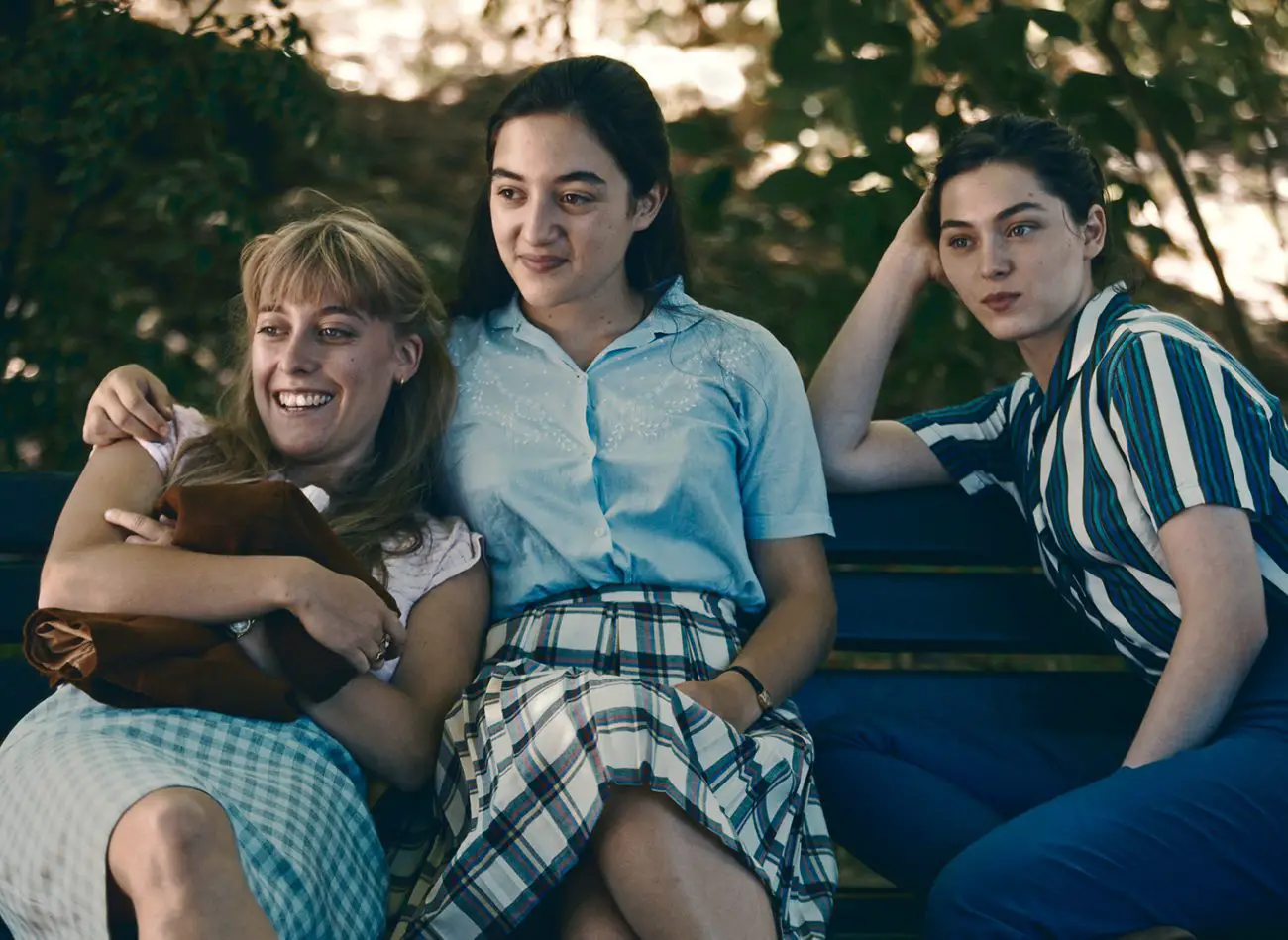 Three high-school friends sitting on a park bench watching the boys: Brigitte (Louise Orry-Diquéro), Helene (Luana Bajrami) and Anne (Anamaria Vartolomei)