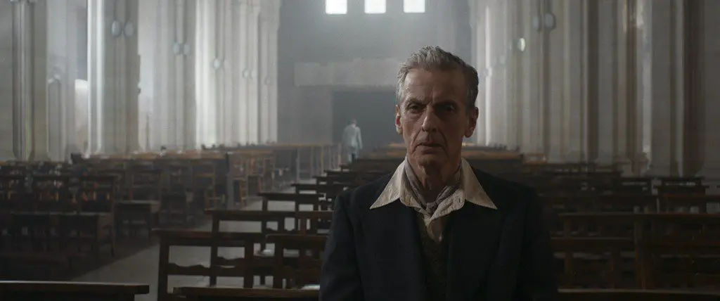 Peter Capaldi as the older Siegfried Sassoon, seated in the pews of a Catholic Church
