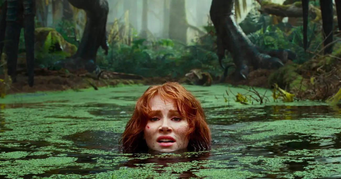 A woman lowers herself into a swamp to avoid a pursuing dinosaur.