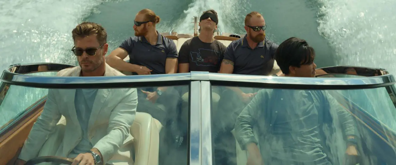 Several men escort a blindfolded passenger in a boat.