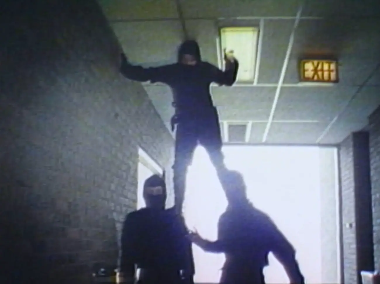 One ninja standing on the shoulders of two other ninjas in a hallway.