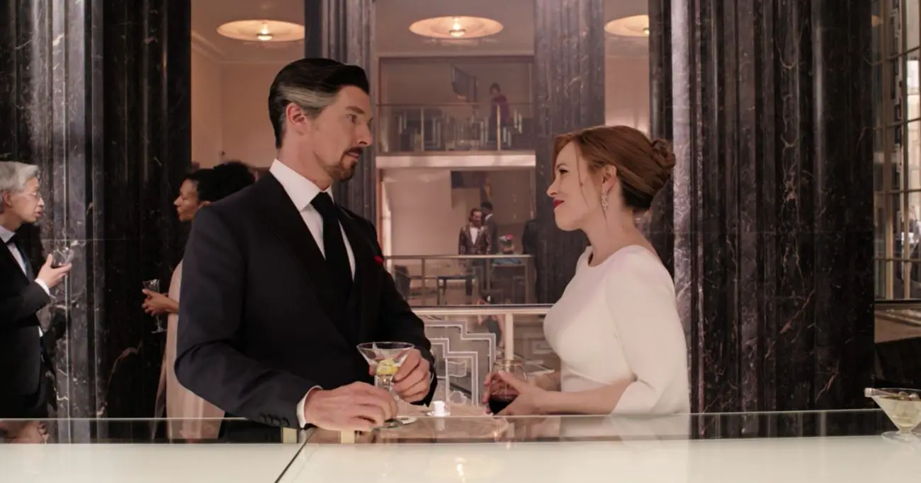 Stephen Strange wearing a suit and Christine Palmer (Rachel McAdams) wearing a wedding dress as they face each other with drinks in their hands