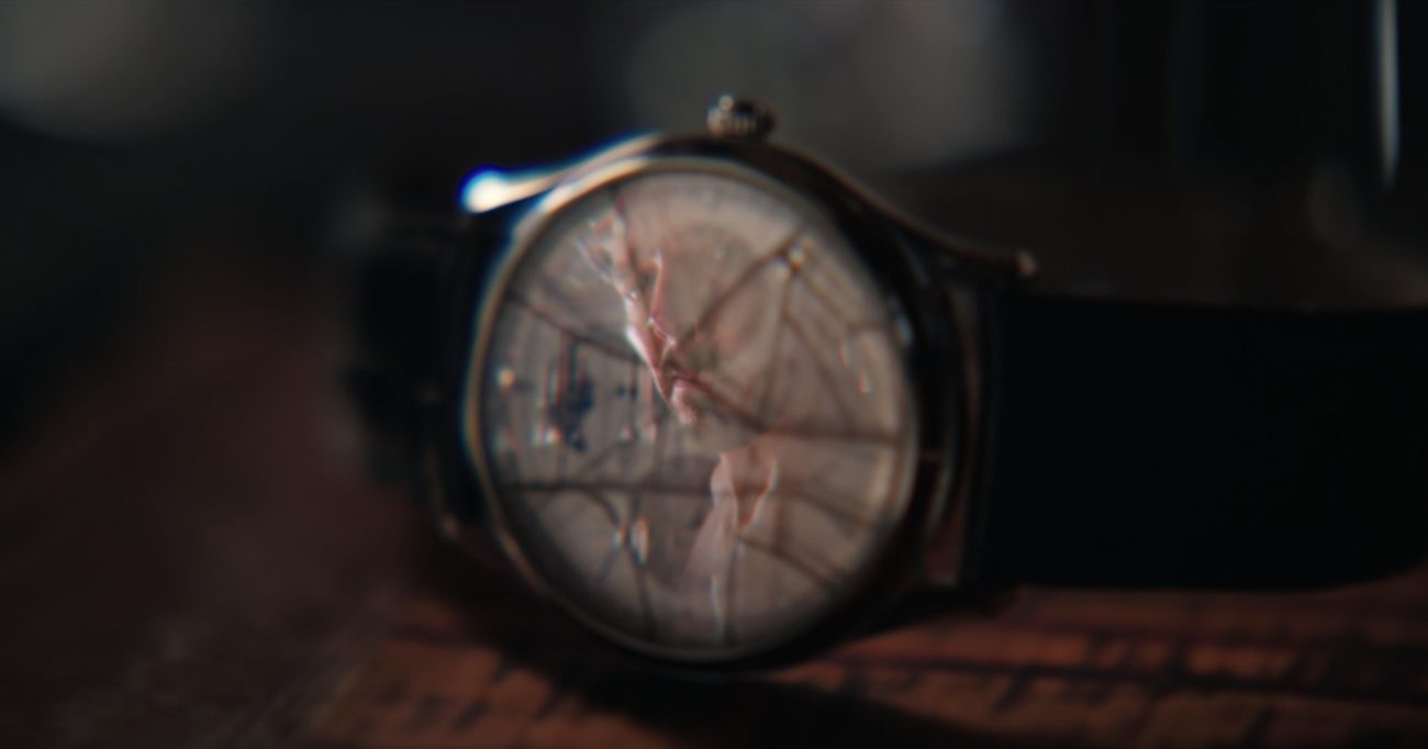 Stephen Strange's face reflected in the cracked face of a broken wristwatch
