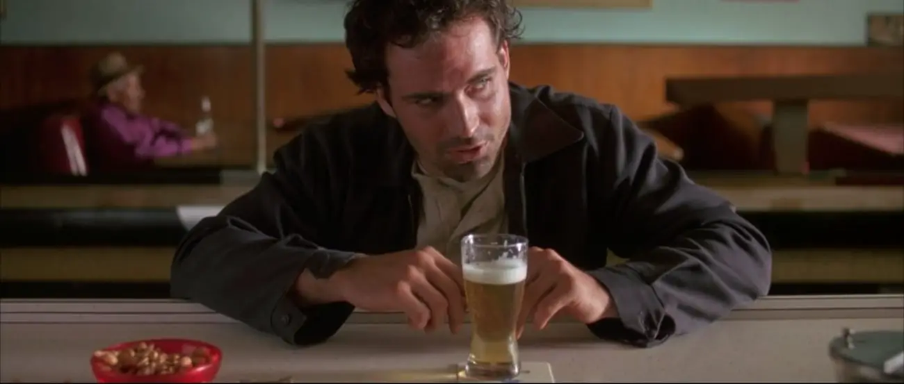 Collie seated at a bar with a glass of beer in front of him.