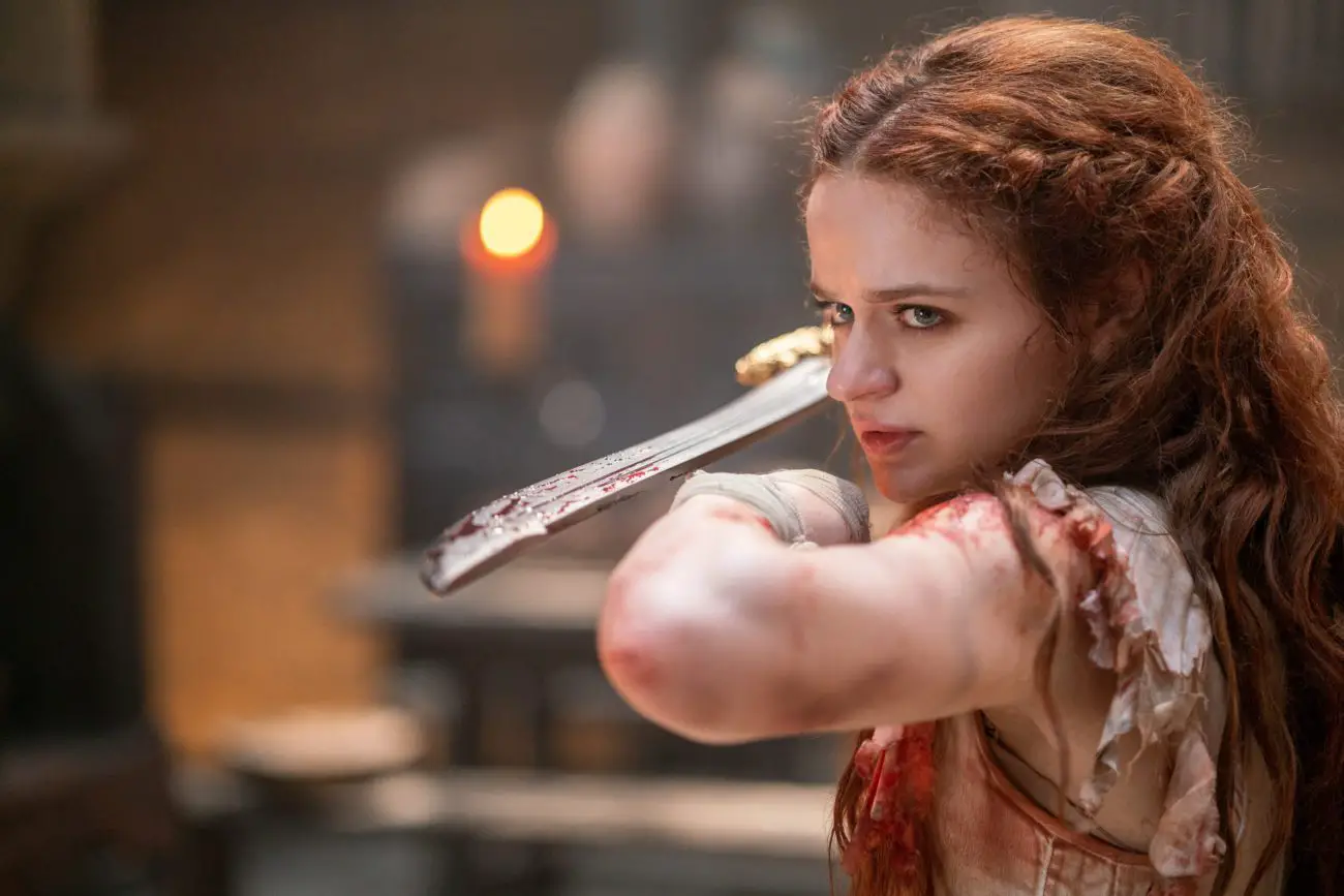 A woman holds a sword down her arm to prepare to fight.