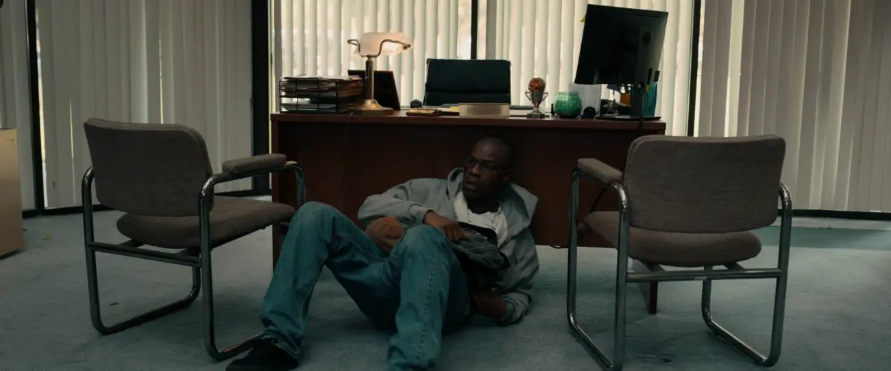 A man sits behind a desk on the floor.