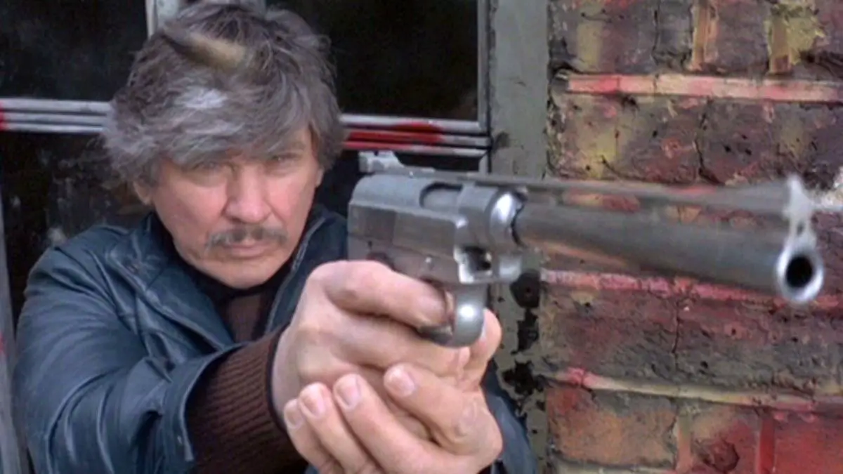 Kersey holds out a long-barreled handgun.