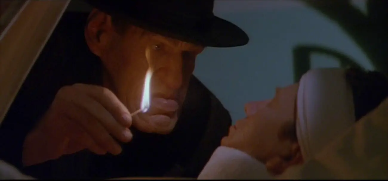 Image from The Rocketeer: A menacing man in a hat lights a match and glares at a bandaged man