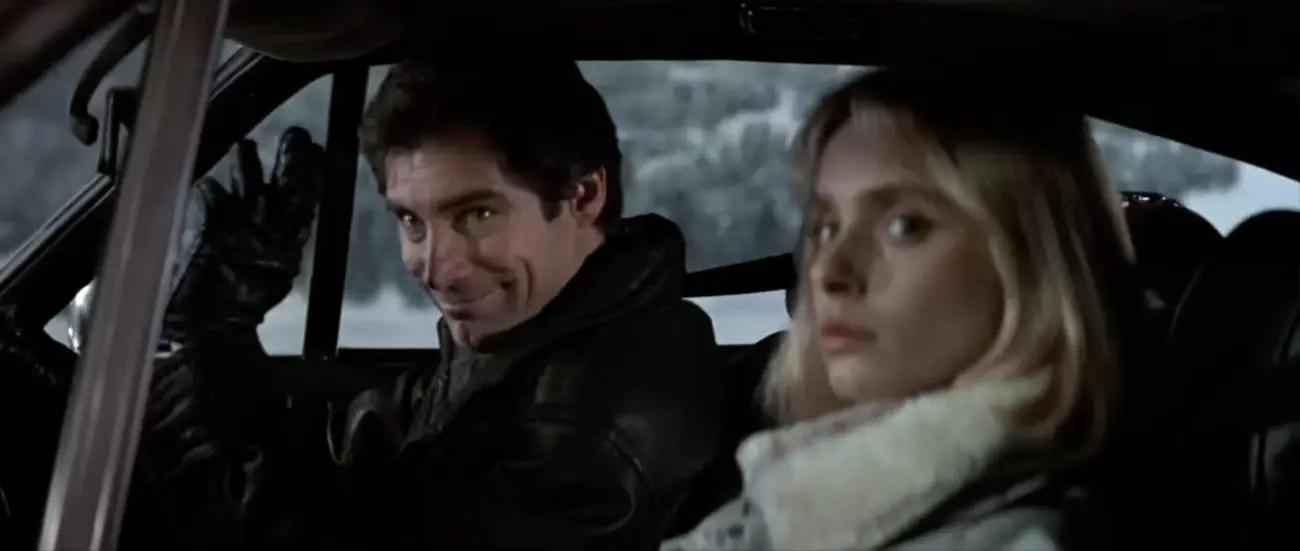 Timothy Dalton waving from a car window, sitting next to Maryam d'Abo, in The Living Daylights (1987)