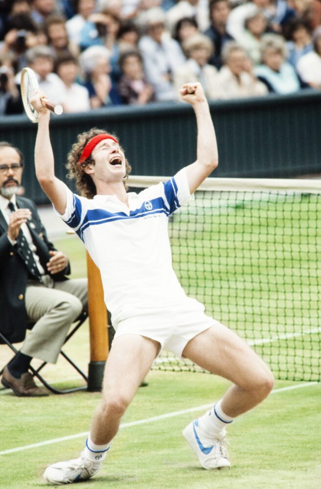 John McEnroe raises his arms in triumph at Wimbledon.