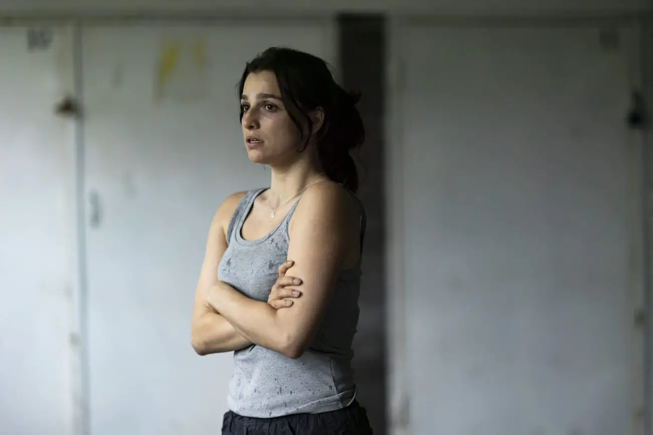 A medium shot of Marisa Abela as Sophie, dressed in a grey tank top.