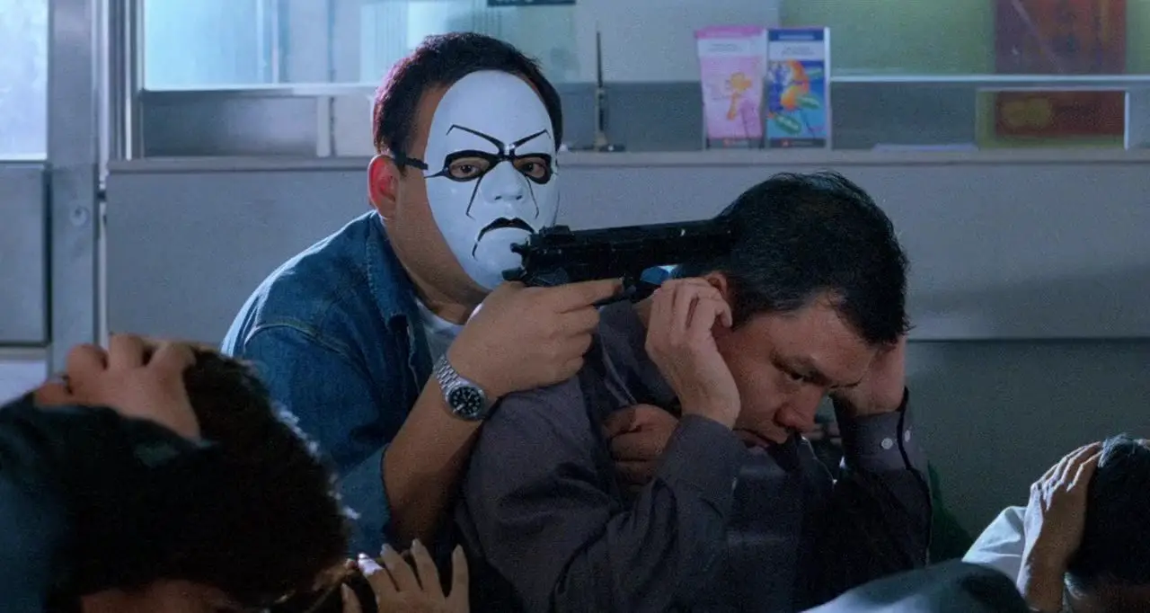 A masked criminal holds a gun to a hostage's head.