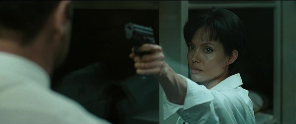 Salt (Angelina Jolie) aims a handgun at a man.