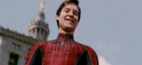 Peter Parker with his Spider-Man mask off looks down at a crowd
