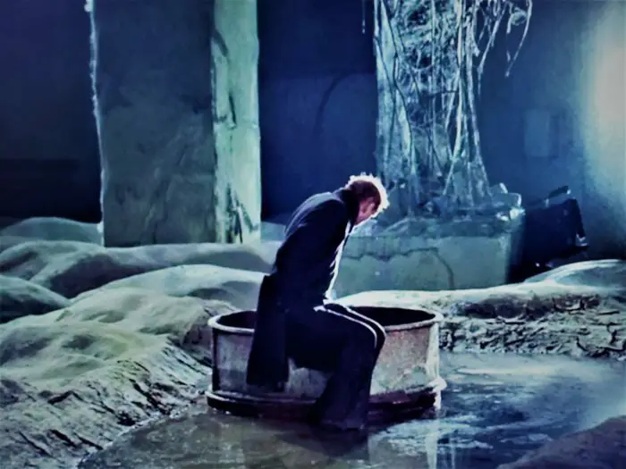 A man in a dilapidated building stares down into a well in the enigmatic Zone in the film Stalker