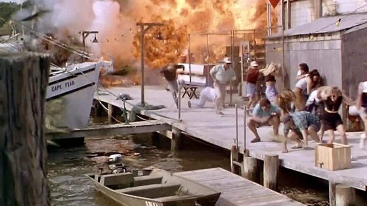 People scatter from an explosion on a pier.