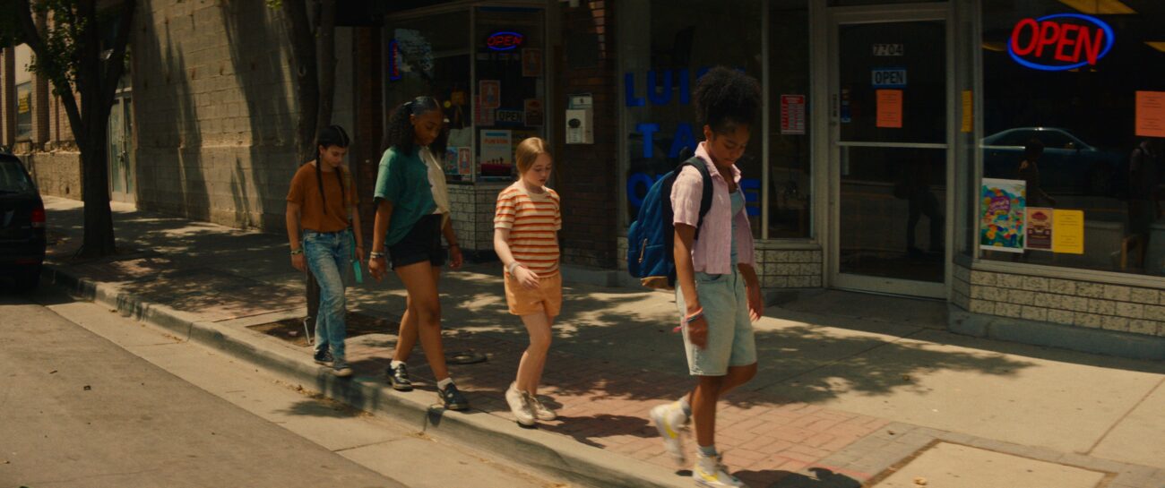 Four teen girls balance themselves walking a curb.
