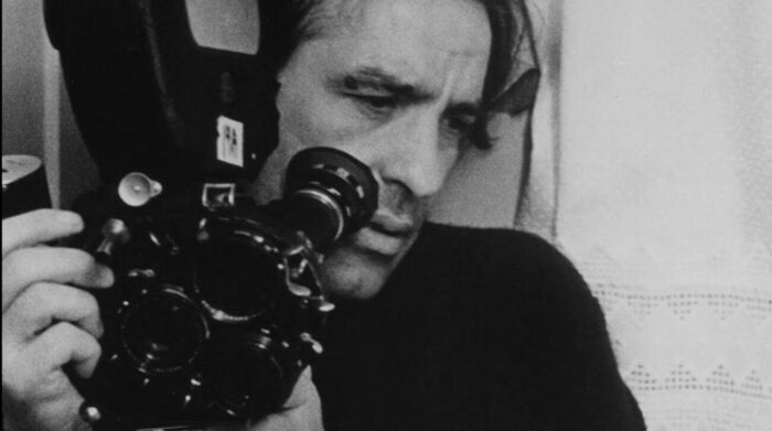 John Cassavetes is depicted holding a film camera.