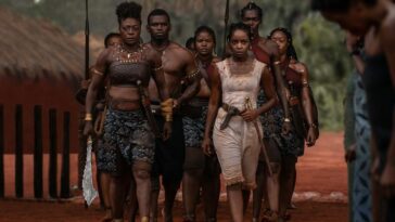 A squad of women warriors march on a road.