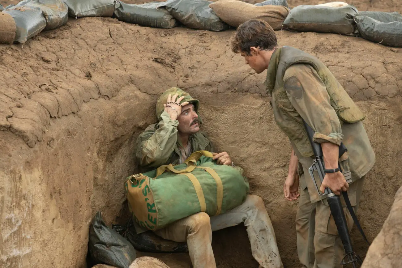 Two soldiers talk in a foxhole.