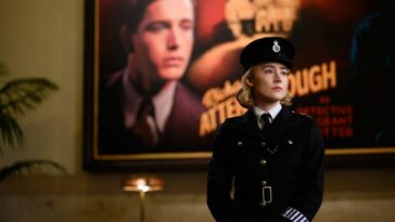 Saoirse Ronan as Constable Stalker, standing in front of a poster for The Mousetrap, featuring Harris Dickerson as Richard Attenborough