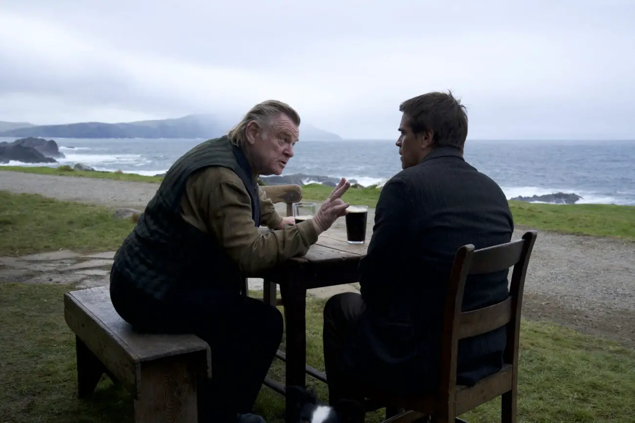 Two men talk pointedly at a table outside in "The Banshees of Inisherin"