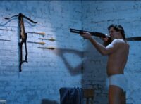 The hero standing in his underwear, aiming a shotgun.