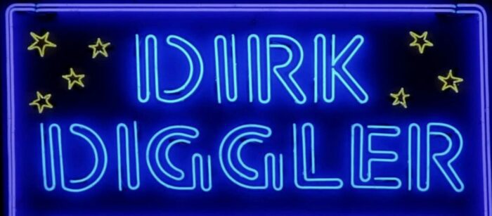 A bright, neon sign displaying "Dirk Diggler" as Eddie imagines his stage name. 