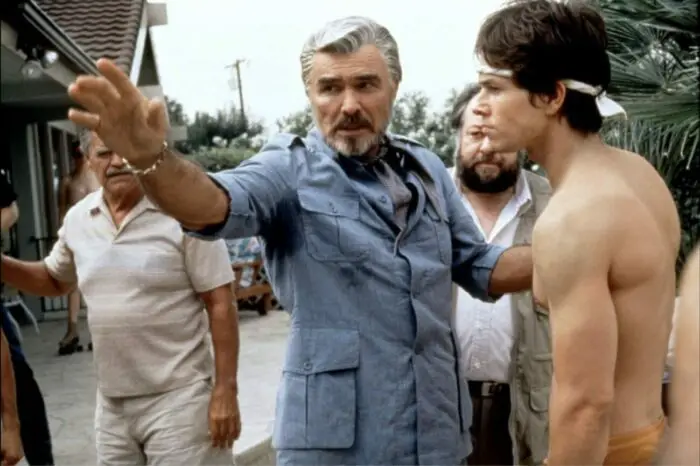 Jack, wearing a blue button down, sets the scene for a shirtless Dirk to make sure he nails the scene.