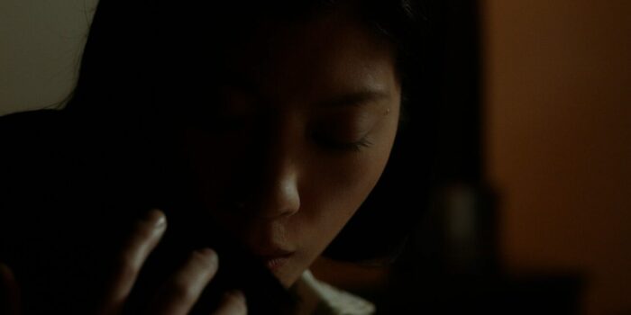 A close-up of a woman on a phone in a dark room