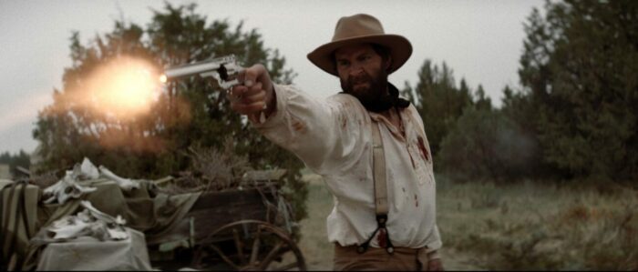 A cowboy fires his gun