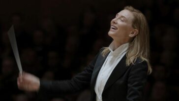 A conductor closes her eyes with a smile to the music.