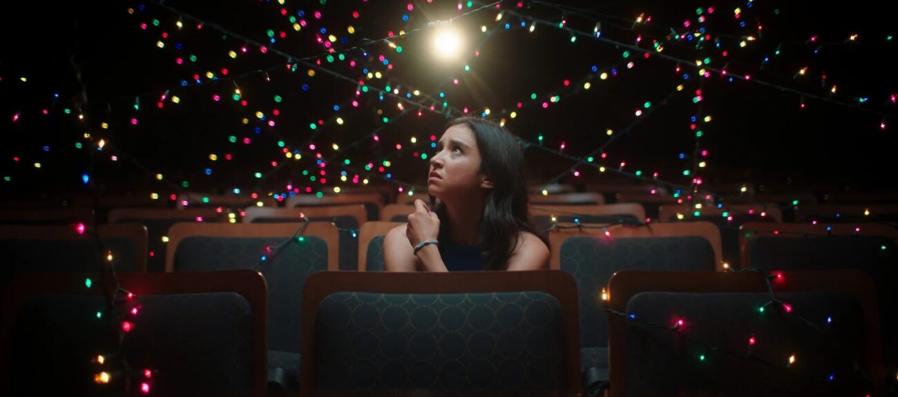 young woman in a theatre looks up at a constellation of colored lights