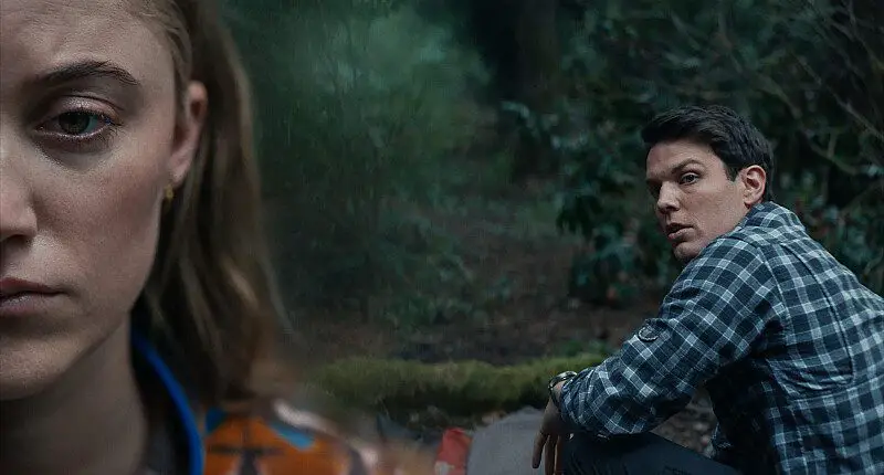 Harry (Jake Lacy, right), in medium shot, speaks to Ruth (Maika Monroe), left in close-up, as the two prepare for heir venture into the woods.