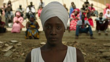 In Xalé, Awa (Nguissaly Barry) faces the camera; behind her is her townspeople