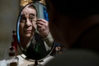 Toni Servillo as Eduardo Scarpetta applies stage makeup in his dressing room mirror.