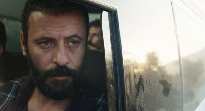 Ali Suliman as Mustafa looks pensively out a car window in 200 Meters. 