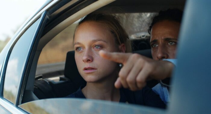 Anna Unterberger as Anne watches as Motaz Malhees as Kifah points from an open car window.
