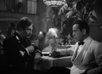 A uniformed captain and club owner discuss matters over drinks in Casablanca