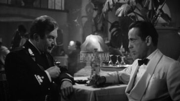 A uniformed captain and club owner discuss matters over drinks in Casablanca