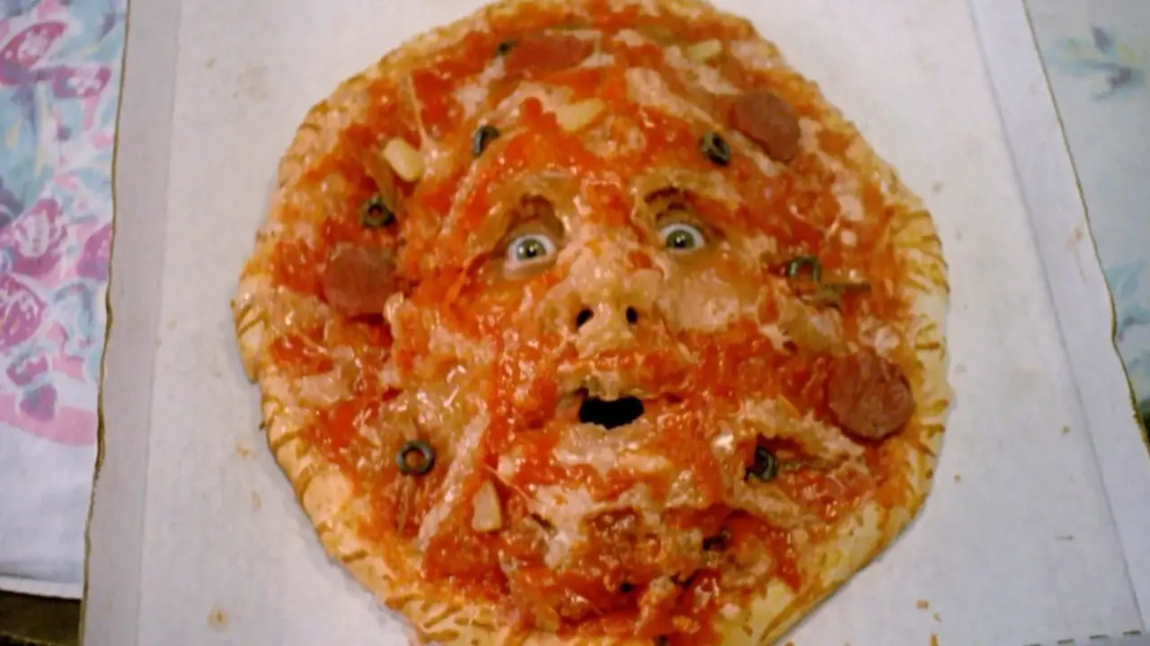 Close-up shot on a pizza with a face in it.