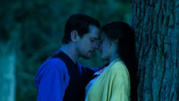 A man leans in to kiss a woman under a tree in Lady Chatterley's Lover