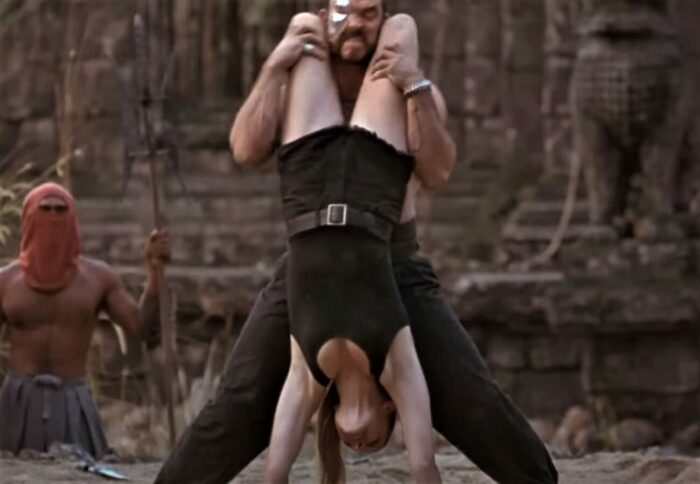 Sonya Blade using some unconventional karate on Kano in the 1995 Mortal Kombat movie, here portrayed by Bridgette Wilson and Trevor Goddard respectively.