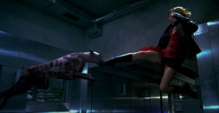 Milla Jovovich as Alice in the first Resident Evil film, jumping through the air to flying kick a mutant dog 