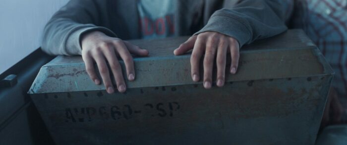 A boy's hands sit atop a large metal box