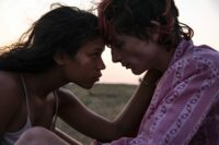 Taylor Russell (left) as Maren and Timothée Chalamet (right) as Lee touching foreheads, intimatly, on a hillside