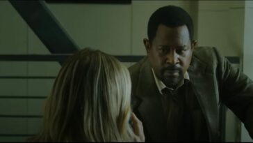 Martin Lawrence sits in a suit and tie as he talks to a blond woman facing away from the camera