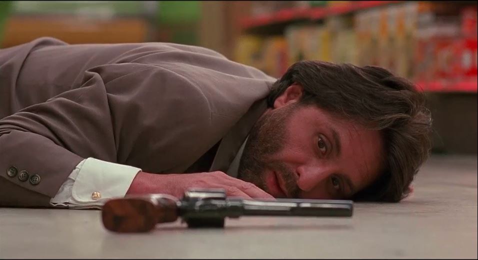 Eugene lays on the floor, looks at a revolver on the floor in front of him.