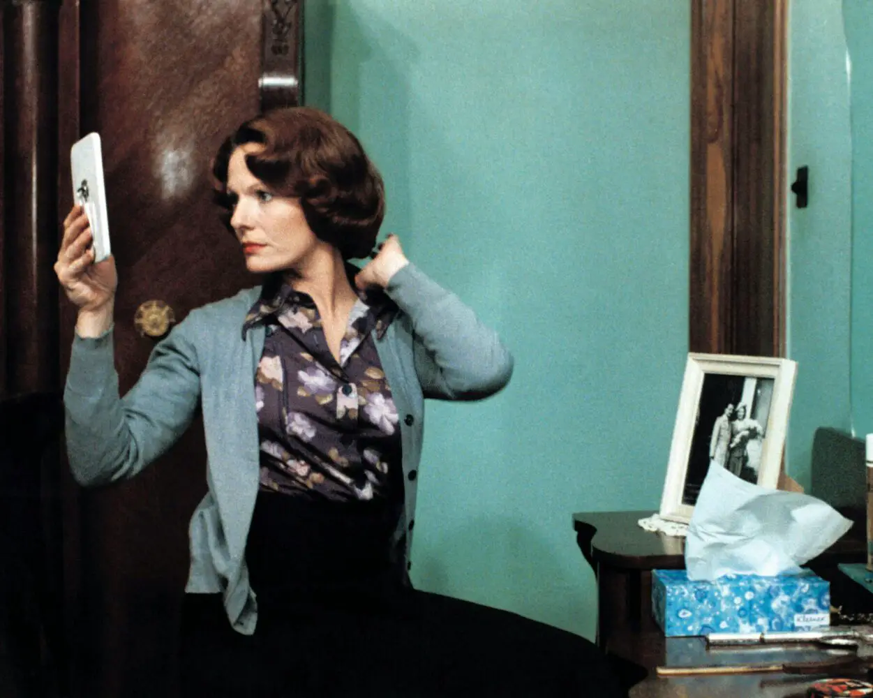 Image from Jeanne Dielman: The protagonist checks her makeup in a hand mirror.